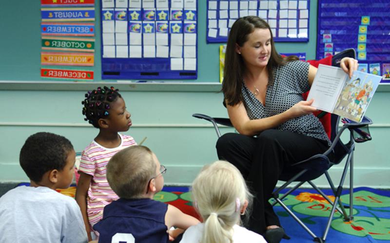 a teacher reads a picture book to a class of young students 