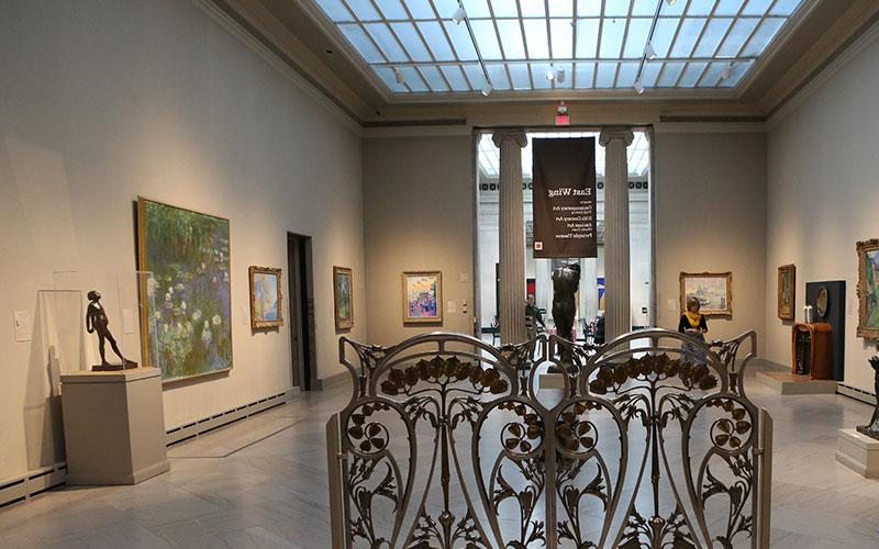 view inside the East Wing of the Toledo Art Museum featuring paintings displayed on the two walls to the left and right