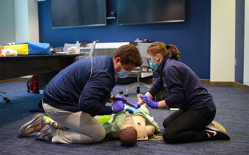 two students practice on a medical mannequin