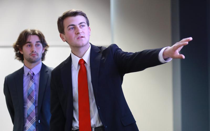 two students in suits give a presentation