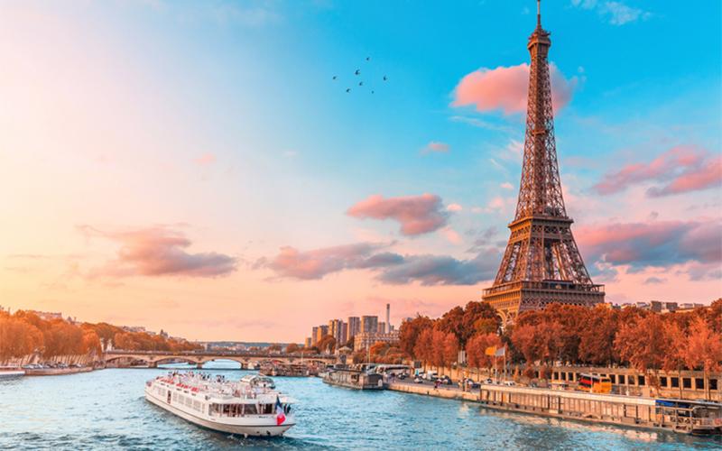 Parisian landscape image featuring the eiffle tower and a ferry boat floating nearby in the river 