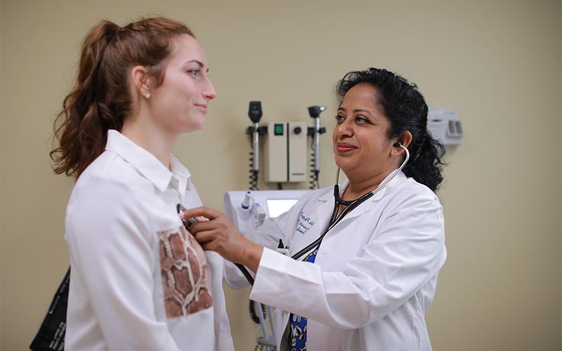A docor using a stethoscope to check on a patients health