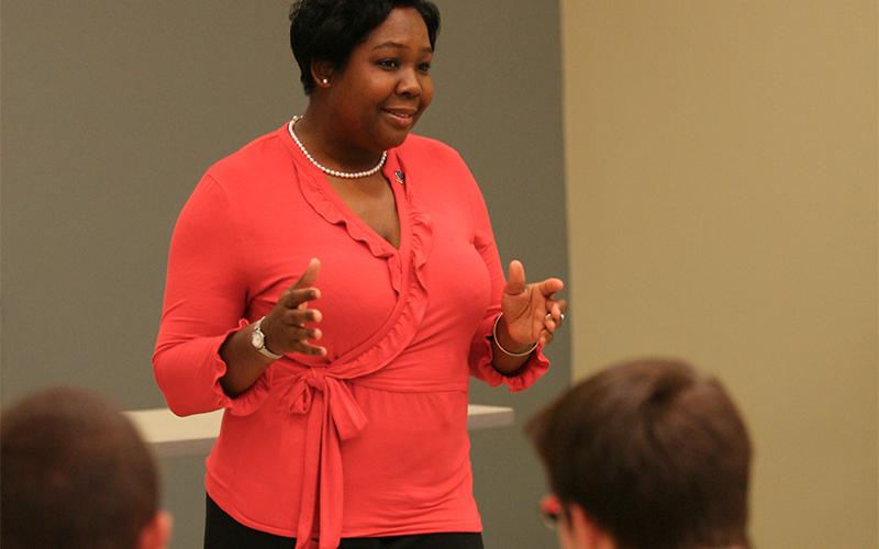 a woman speaks to an audience in a lecture hall